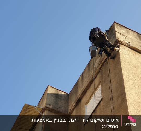 אדם על חבל אוטם קיר חיצוני של בניין